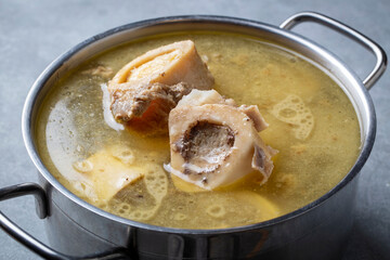 Boiled bone and broth. Homemade beef bone broth is cooked in a pot on. Bones contain collagen,...