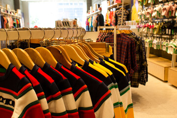 Shirt and pant hanging on hangers on a clothing rack and arranged in shelf in a modern clothe store