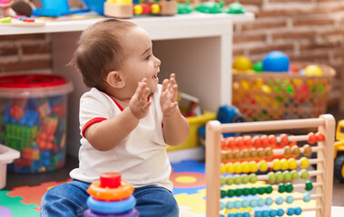 Adorable hispanic baby playing with abacus and hoops game applauding at kindergarten
