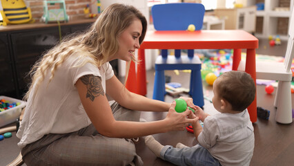 Fototapeta premium Mother and son playing with balls sitting on floor at kindergarten