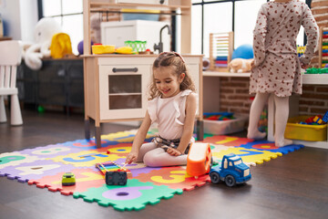 Adorable caucasian girl playing xylophone sitting on floor at classroom