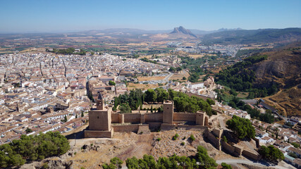 Fototapeta na wymiar Aerial drone view of Antequera castle with the natural monument The Lovers Rock in the background. Touristic travel to Spain. Historic interest and Unesco World Heritage Site. 