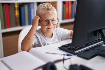 Fototapeta premium Adorable toddler student using computer sitting on table at classroom