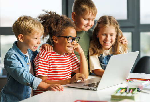 Cheerful  schoolkids   looking at laptop screen during online lesson