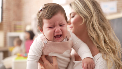 Mother and daughter consueling baby crying at kindergarten