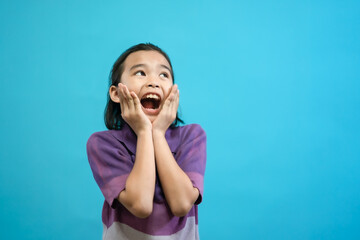 Fototapeta premium Smiling Asian kid of little girl close up photo of cute and cheerful people, looking and smile on blue pastel background