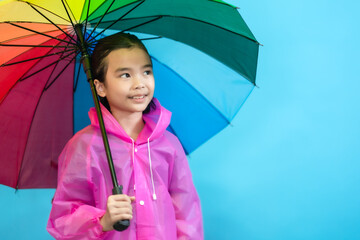 Happy kids girl, children close up cute and cheerful people, holding umbrella and wearing rain coat looking and smile on blue pastel background