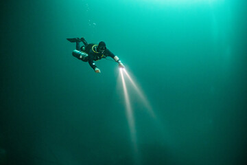 cave diver instructor leading a group of divers in a mexican cenote underwater