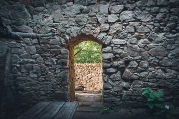 Fototapeta premium A doorway in the wall of a ruined castle through which sunlight spills.