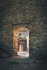 Obraz premium A doorway in the wall of a ruined castle through which sunlight spills.