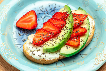 toasts or bruschetta with strawberry, avocado, soft cheese and chia seeds on a blue background. healthy Breakfast or lunch. Keto diet. place for text, top view