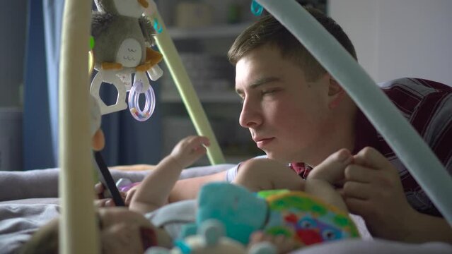 A young father lies on the bed with a phone