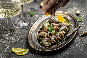 Escargots de Bourgogne or Snails with herbs, butter, garlic on metal plate with forks. wine glass. gourmet food. Restaurant menu, dieting, cookbook recipe
