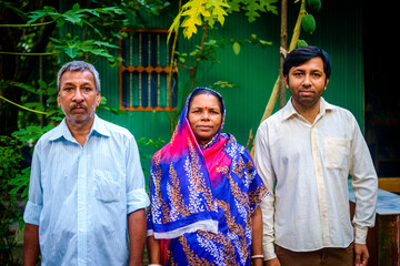 South asian hindu religious family members standing before their tin shed home