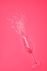 champagne glass with spilling sparkles in the color of 2023 viva magenta. High quality photo