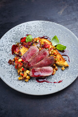 Traditional roasted Italian panettone tagliata di manzo with sliced beef steak and vegetable served as close-up on a Nordic design plate
