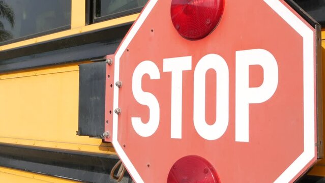 Red stop sign, yellow school bus in California, USA. Traffic warning on passenger schoolbus or shuttle in America. Public transportation safety on road. Caution or attention signage. Education concept