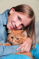 Portrait of Happy girl holding her ginger cat. Blue-eyed girl and kitten. Child and pet.