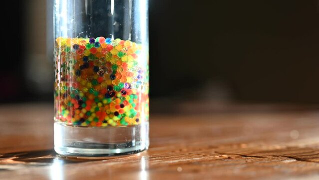 Time lapse video of water beads expanding inside a glass.
