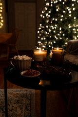 New Year 2022-2023. New Year's decoration. Christmas tree. Candle near the Christmas tree for the holiday. Marshmallow and hot chocolate in a cup.