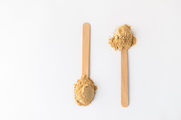 Top view of two spoons with maca root powder on white background, copy space