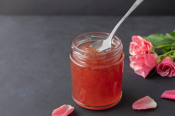 Bulgarian rose petal jam in a jar with spoon on black background with copy space - obrazy, fototapety, plakaty