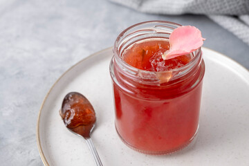 Closeup of rose jam on neutral background with spoon and plate