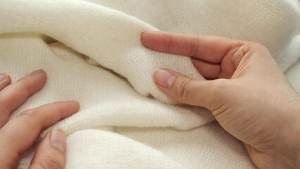 female's hand on the fabric of white plush cloth with soft nap. Clothing industry concept, slow...