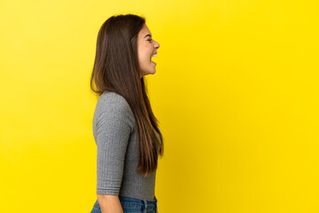 Young Brazilian woman isolated on yellow background laughing in lateral position