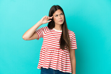 Young Brazilian woman isolated on blue background making the gesture of madness putting finger on...