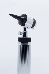metallic otoscope on illuminated white background