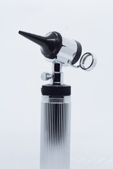 metallic otoscope on illuminated white background