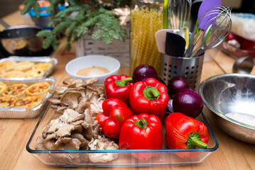 Set of raw red onions, red bell peppers, fresh oyster mushrooms in a glass dish. Kitchen table before cooking.