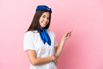 Airplane stewardess Brazilian woman isolated on pink background pointing finger to the side