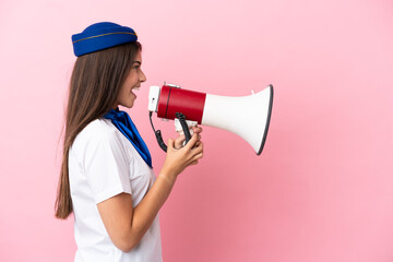 Airplane stewardess Brazilian woman isolated on pink background shouting through a megaphone
