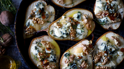 Baked pears with dor blue cheese, honey, thyme and walnuts. French style kitchen.