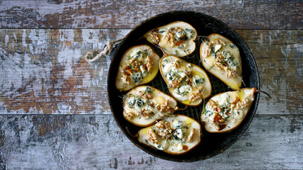 Baked pears with dor blue cheese, honey, thyme and walnuts. French style kitchen.