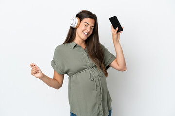 Young Brazilian woman isolated on white background pregnant and dancing while listening music