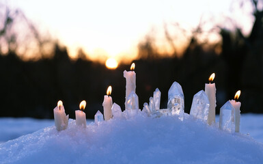 quartz minerals and candles on snow, natural abstract winter background. Gemstones for esoteric...