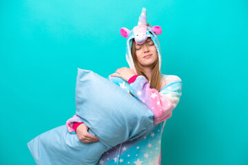 Young caucasian girl with unicorn pajamas holding pillow isolated on blue background suffering from pain in shoulder for having made an effort © luismolinero