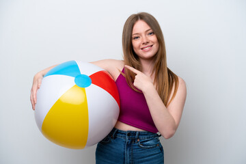 Young caucasian woman holding beach ball isolated on white background pointing to the side to present a product