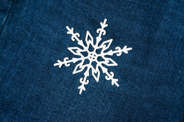 Christmas snowflake decoration on a dark denim background. Concept of preparation for the holiday