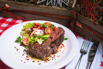A piece of roast beef and a salad of fresh vegetables in oil.