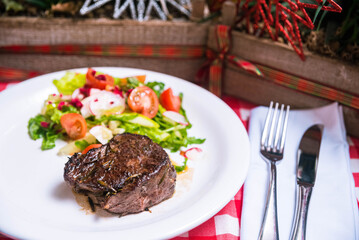 A piece of roast beef and a salad of fresh vegetables in oil.