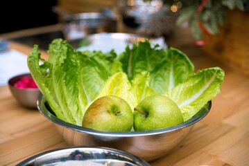 a bowl of fresh green apples and lettuce leaves. raw foods before cooking.