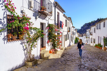 Beautiful streets of white houses decorated with green plants and tourist woman strolling through the village. © josemiguelsangar