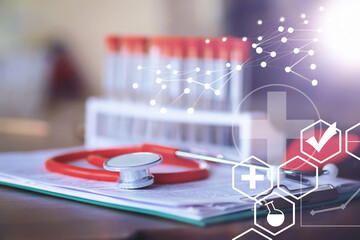 Stethoscope, test tubes, laptop, prescriptions, glasses on the table. Doctor`s desk in the clinic's office.