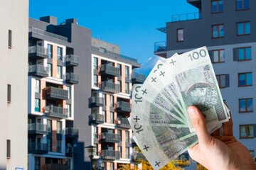 Polish money on the background of an apartment building. Concept showing the real estate market in Poland