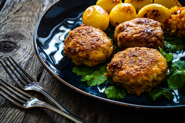 Fried pork meatballs with fried potatoes and cabbage on wooden table
