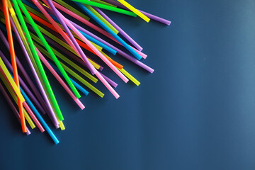 Fototapeta premium Colorful plastic drinking straws, close up as background. colored tubules for juice and cocktails on black wooden table